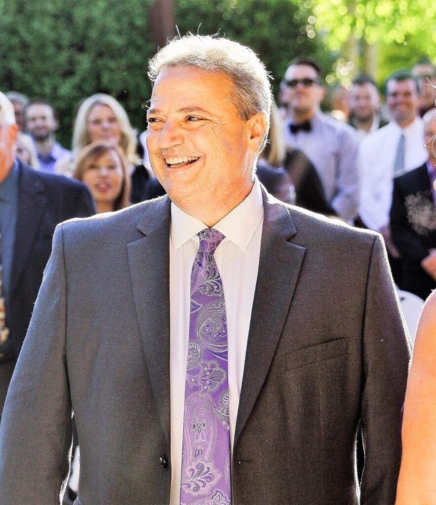 A woman is standing next to a brown horse in a field.