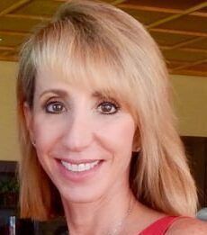 A woman is riding a white horse in a ring.