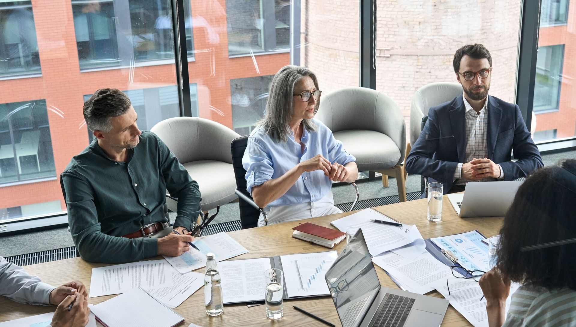 People at a business meeting in an office. Papers and laptops are on the table.