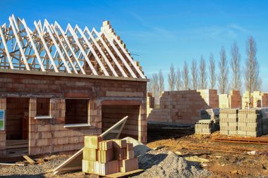 House under construction, brick exterior, wooden roof frame. 