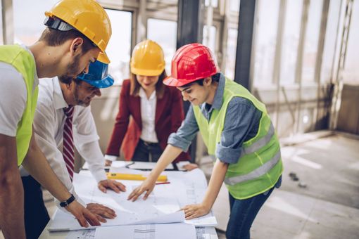 Construction workers and architect reviewing blueprints at a construction site.