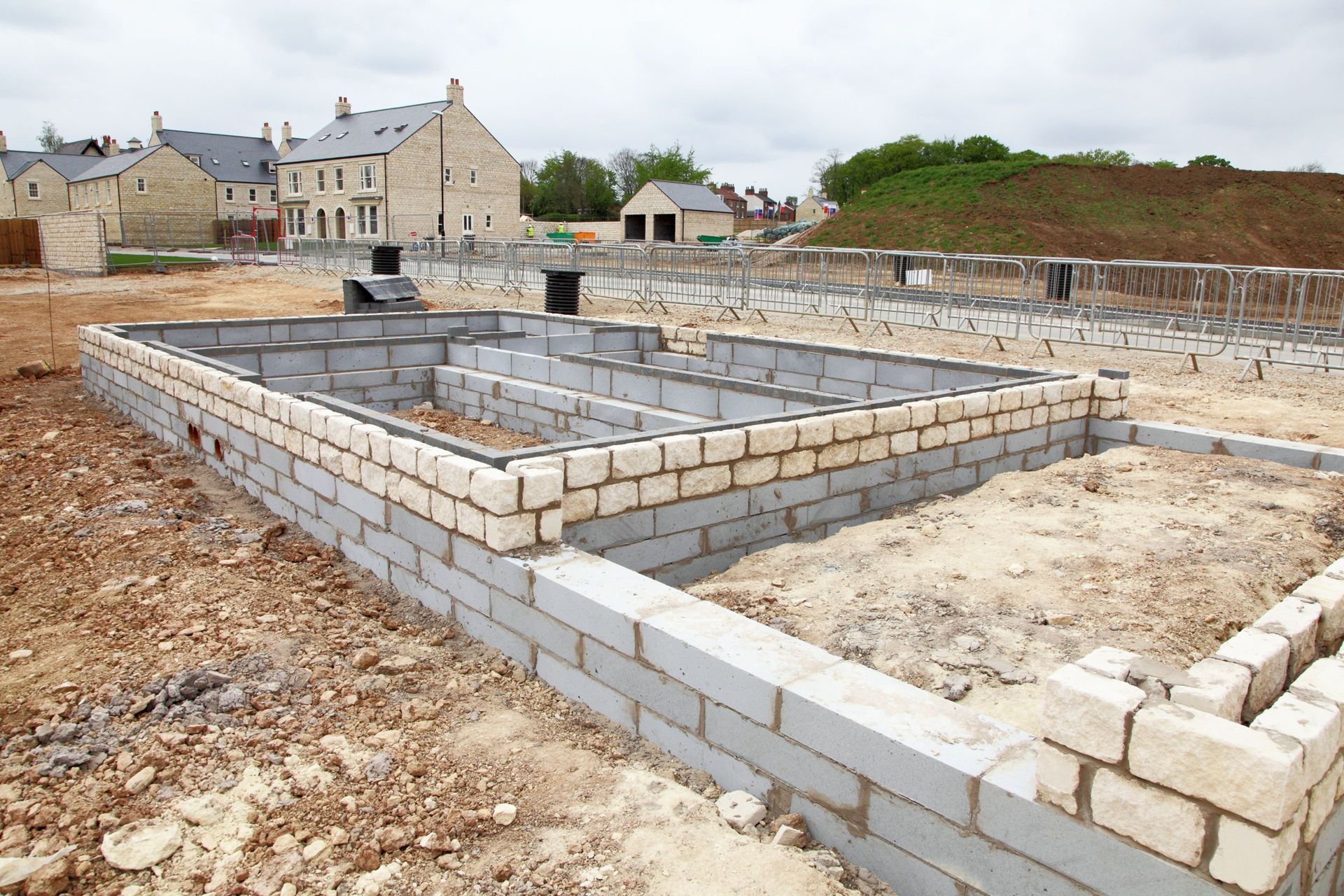 Foundation of a building under construction, using gray and tan concrete blocks.