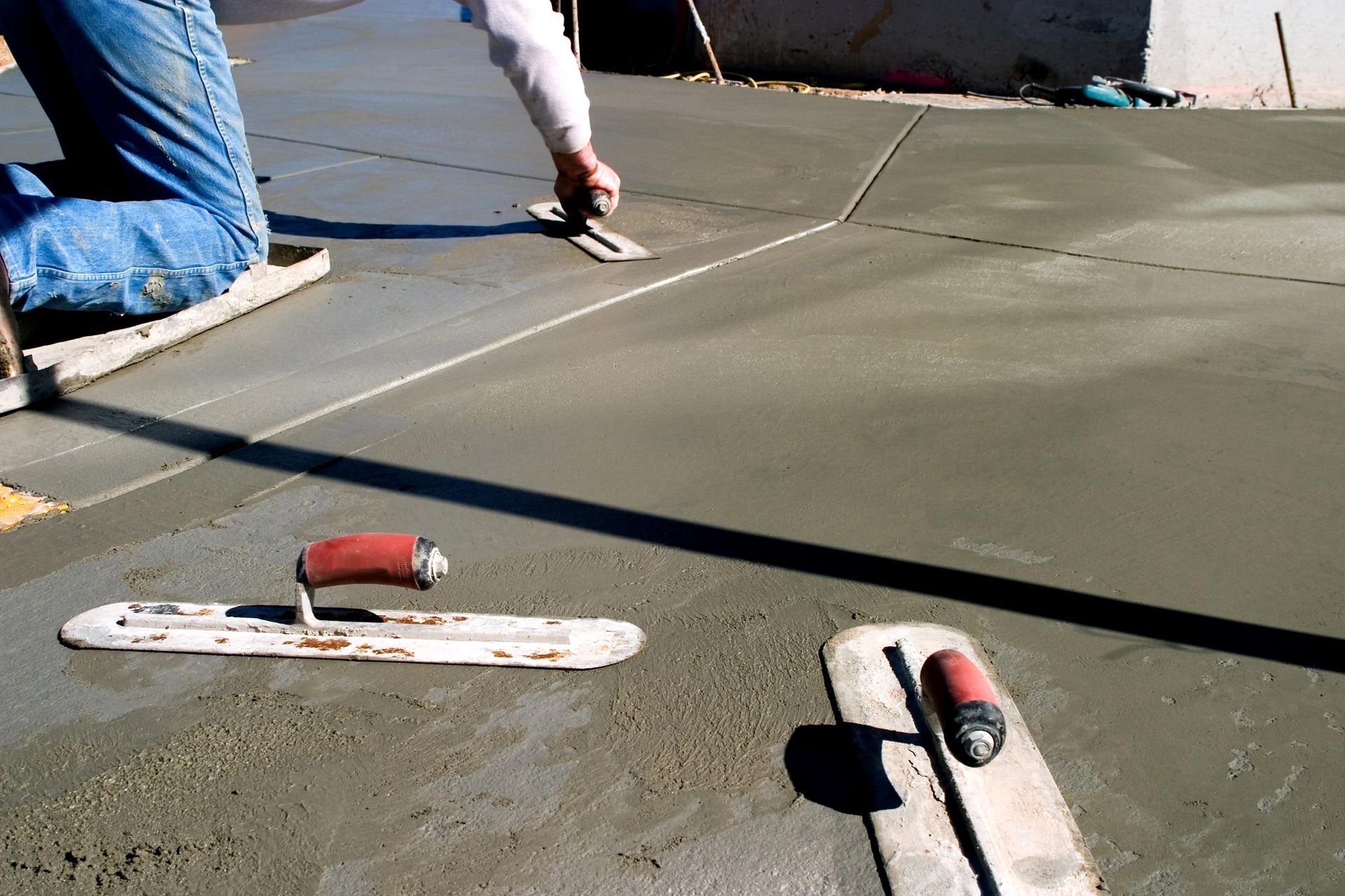 A person is working on a concrete surface with a trowel.