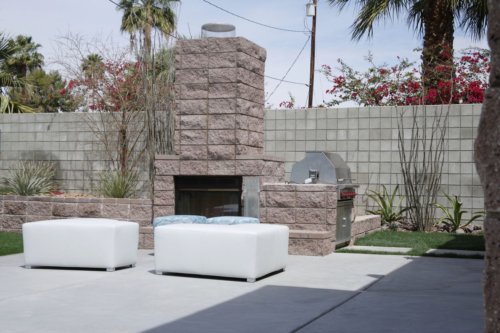 A patio with a fireplace and two white ottomans.