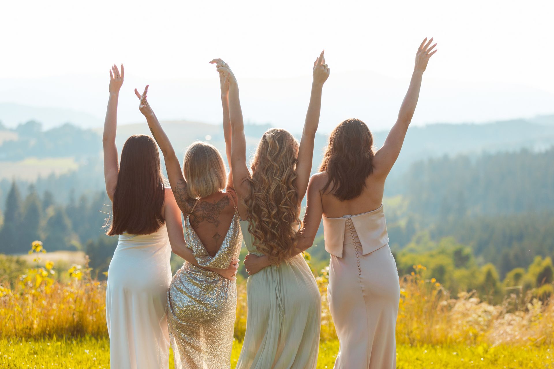 A group of women are standing in a field with their arms in the air.