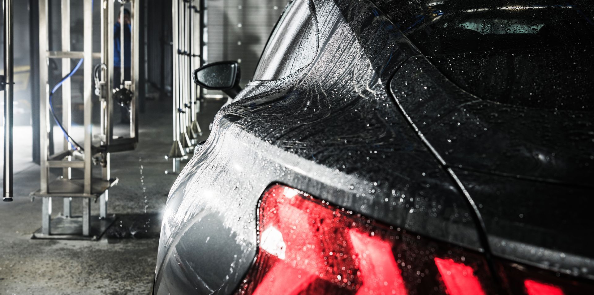 Blue car being washed by hand with soap suds in a car wash