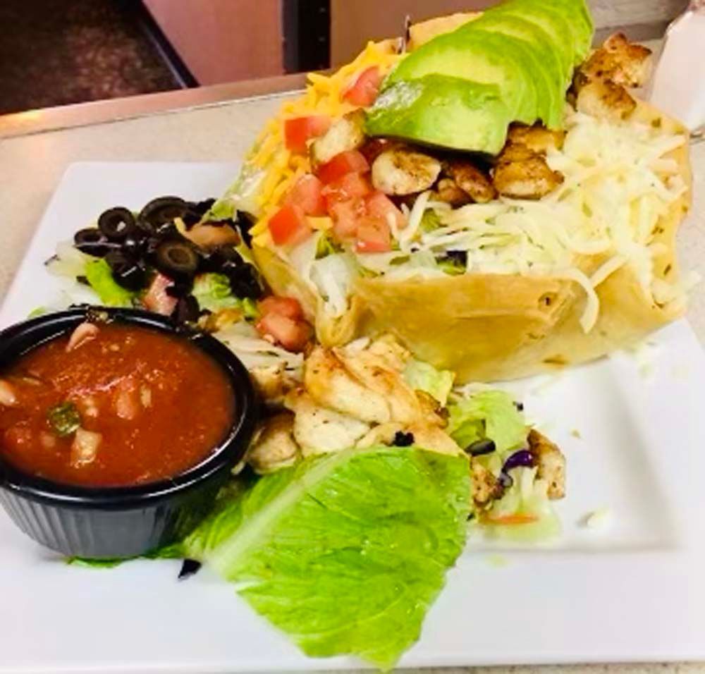 A plate of food with a bowl of salsa on the side