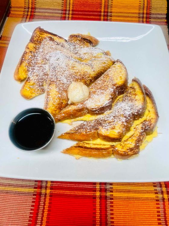 A white plate topped with french toast and syrup on a table.