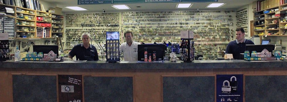 Three men are standing behind a counter in a store.