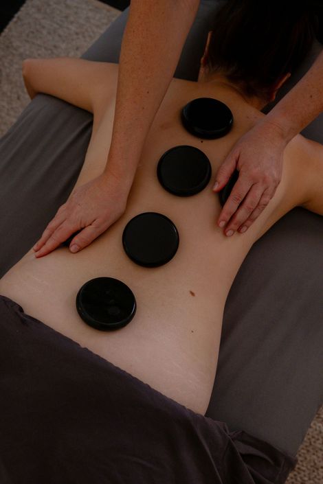 Hands giving a back massage with candles and a blurred spa setting in the background