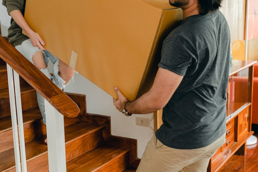 A man is carrying a box up a set of stairs.