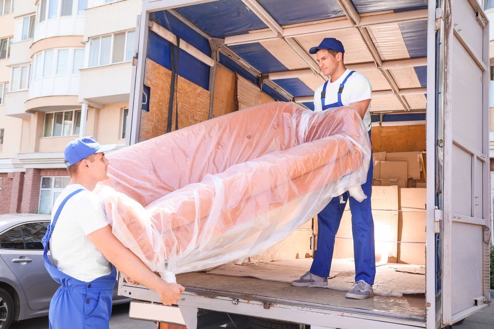 Two men are loading a couch into a truck.