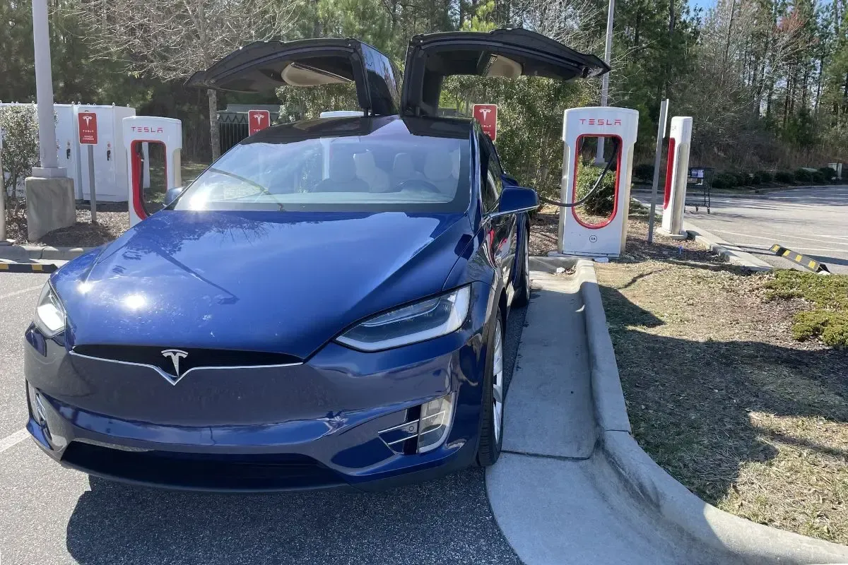 A blue Tesla X at a Tesla charging station