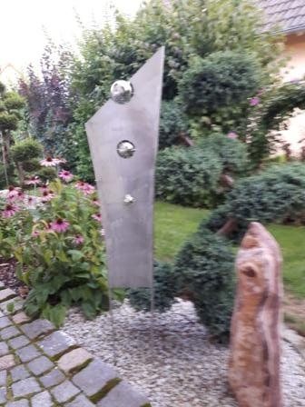 In der Mitte eines Gartens steht eine Statue.