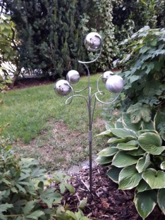 Eine Metallskulptur steht mitten in einem Garten.