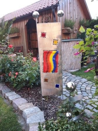 Eine Skulptur in einem Garten mit einem Holzgebäude im Hintergrund