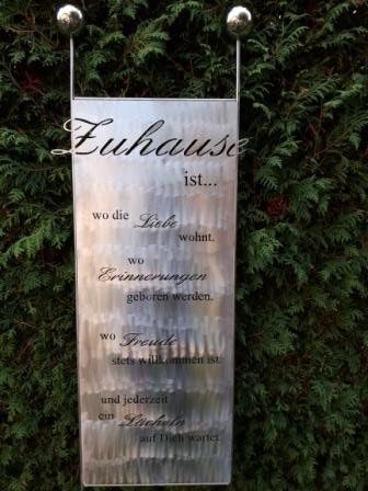 An einem Baum hängt ein Schild mit einem Zitat.