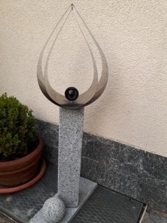 Eine Skulptur steht auf einem Steinsockel vor einem Gebäude.