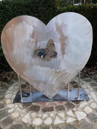 Eine große herzförmige Skulptur mit einem Schmetterling darin.