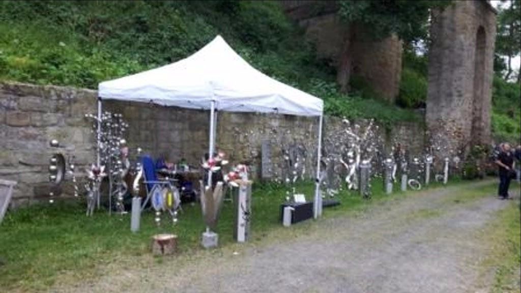 Ein weißes Zelt steht im Gras vor einer Steinmauer.