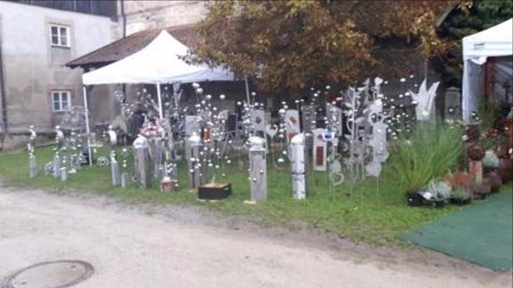 Eine Reihe von Skulpturen sitzen im Gras vor einem Gebäude