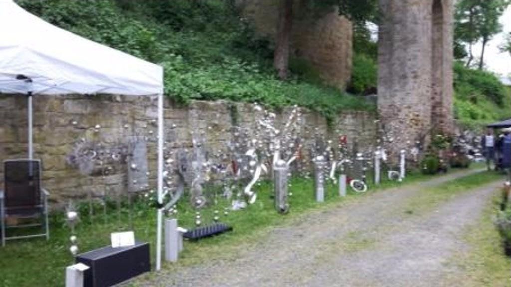 Ein weißes Zelt steht am Rand einer unbefestigten Straße neben einer Steinmauer.