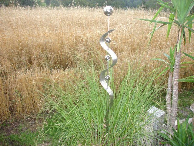 Eine Skulptur aus Edelstahl steht vor einem Weizenfeld.