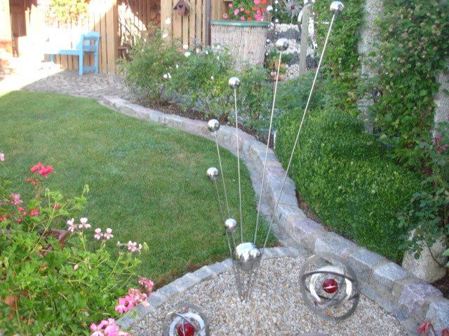 Ein Rasen mit Steinrand und Blumen im Hintergrund