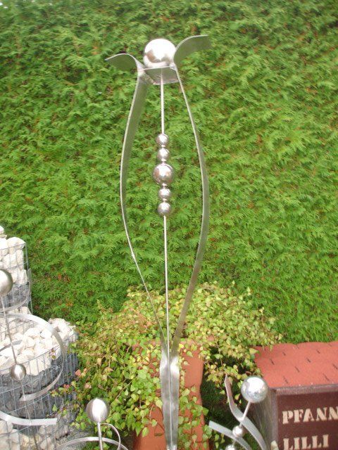 Eine Edelstahlskulptur steht vor einem Schild mit der Aufschrift „Pfann Lilli“