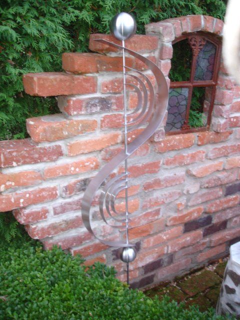 Eine Backsteinmauer mit einer Skulptur davor.