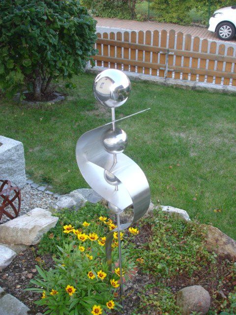 Eine Edelstahlskulptur steht mitten in einem Garten