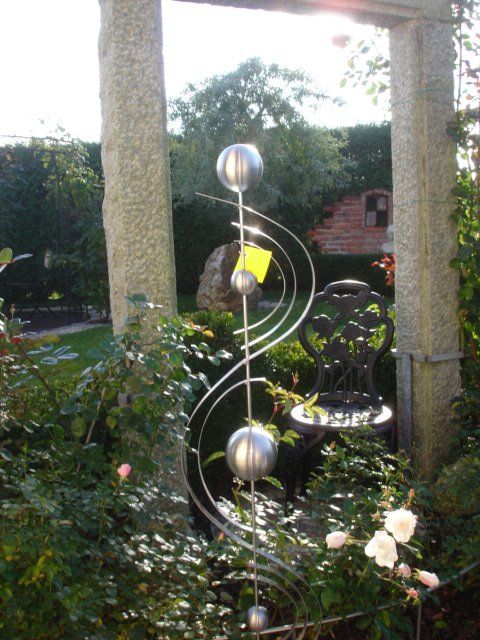 Eine Skulptur in einem Garten mit einem Stuhl im Hintergrund