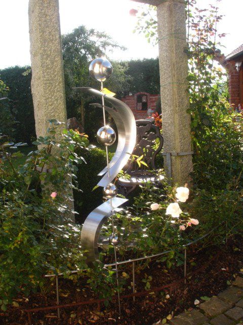 Ein Garten mit einer Edelstahlskulptur in der Mitte