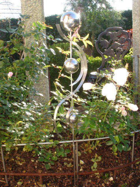 Eine Metallskulptur in einem von Blumen umgebenen Garten
