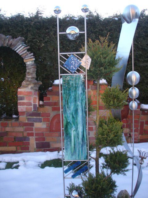 Eine Skulptur in einem verschneiten Garten mit einer Backsteinmauer im Hintergrund