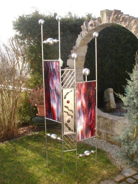 Eine Skulptur in einem Garten mit einem Steinbogen im Hintergrund