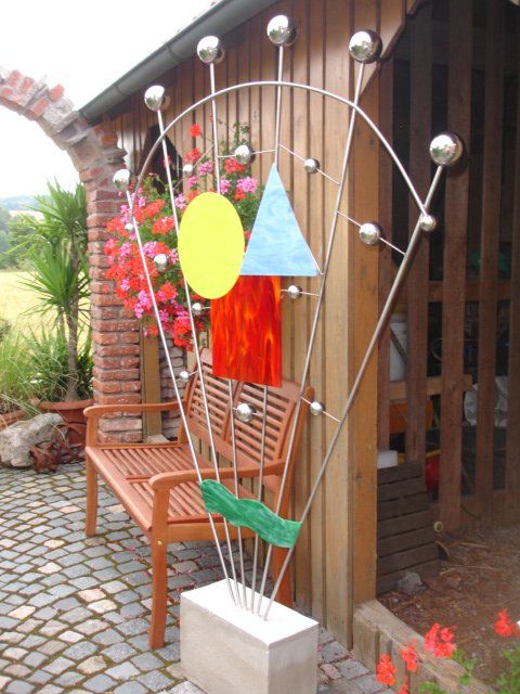 Eine Holzbank steht neben einer Skulptur aus geometrischen Formen