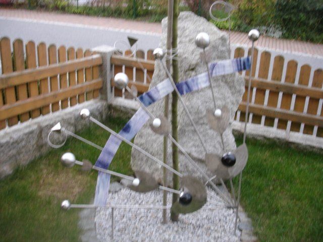 Eine Skulptur in einem Garten mit einem Holzzaun im Hintergrund