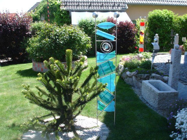Ein Baum in einem Garten mit einer blauen Skulptur im Hintergrund