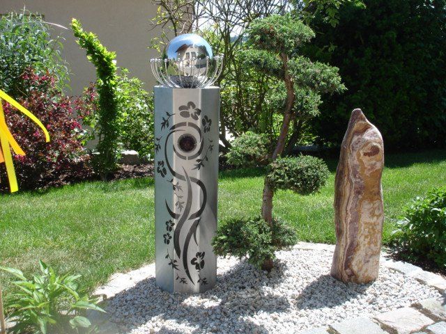 Eine Skulptur in einem Garten mit einer Kugel darauf