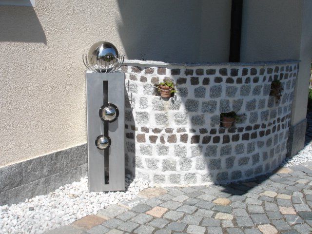 Eine Ziegelwand mit einer Edelstahlkugel darauf