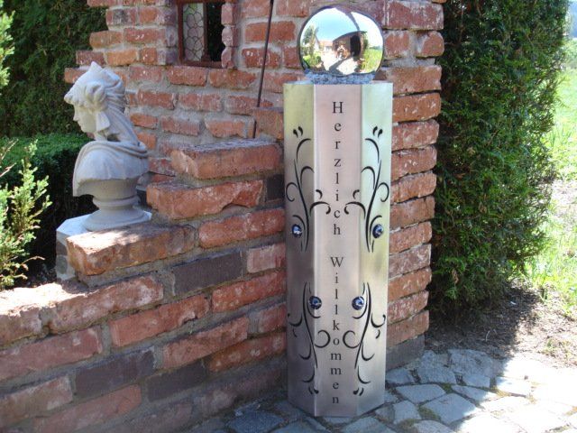 A brick wall with a statue and a sign that says herrlich willkommen