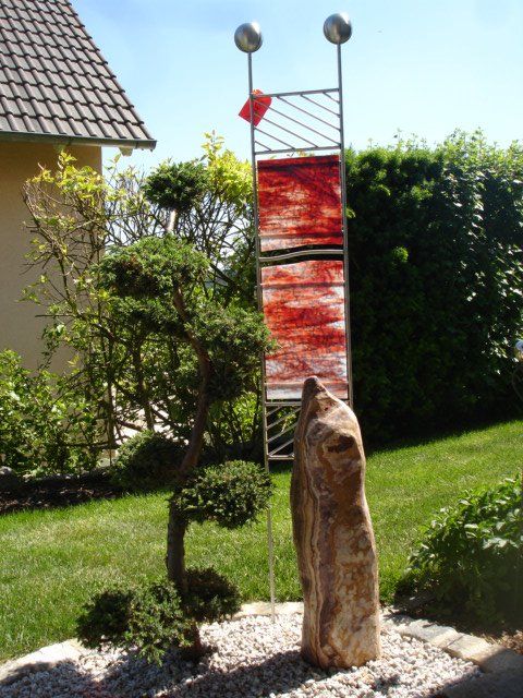 Eine Skulptur in einem Garten mit einem Baum im Hintergrund