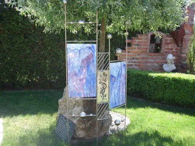 Eine Skulptur in einem Garten mit einem Baum im Hintergrund