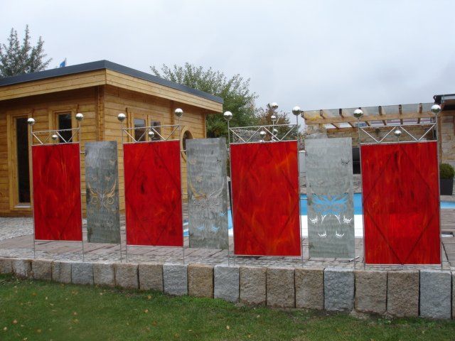 Eine Reihe roter Buntglasfenster vor einem Pool