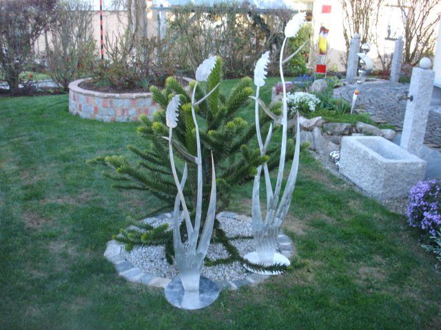 Eine Skulptur in einem Garten mit einem Kaktus im Hintergrund