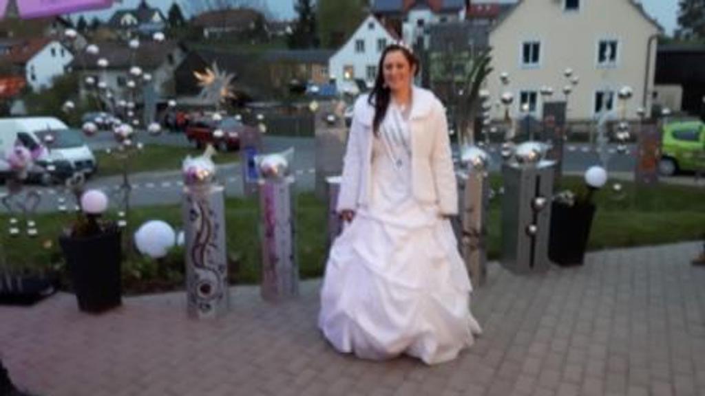 Eine Frau in einem Brautkleid steht auf einem Bürgersteig