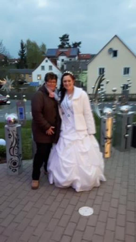 Eine Braut und ein Bräutigam posieren auf einem Backsteingehweg für ein Foto.