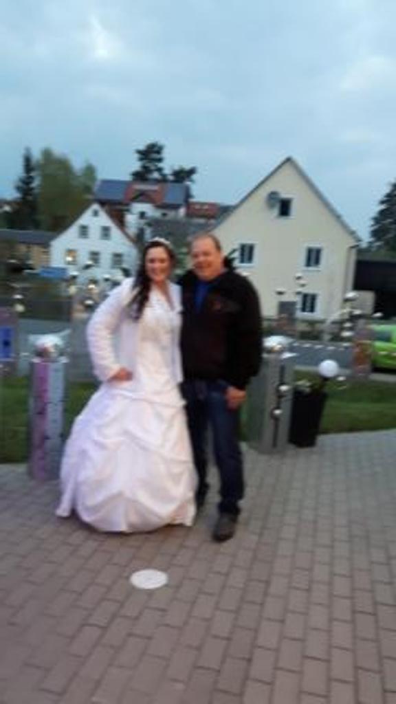 Eine Braut und ein Bräutigam posieren auf einem Backsteingehweg für ein Foto.