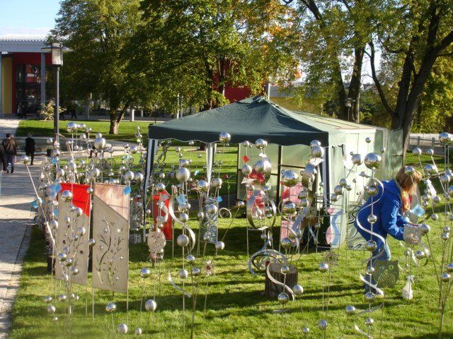 Eine Frau in einer blauen Jacke steht vor einem Zelt voller Luftballons